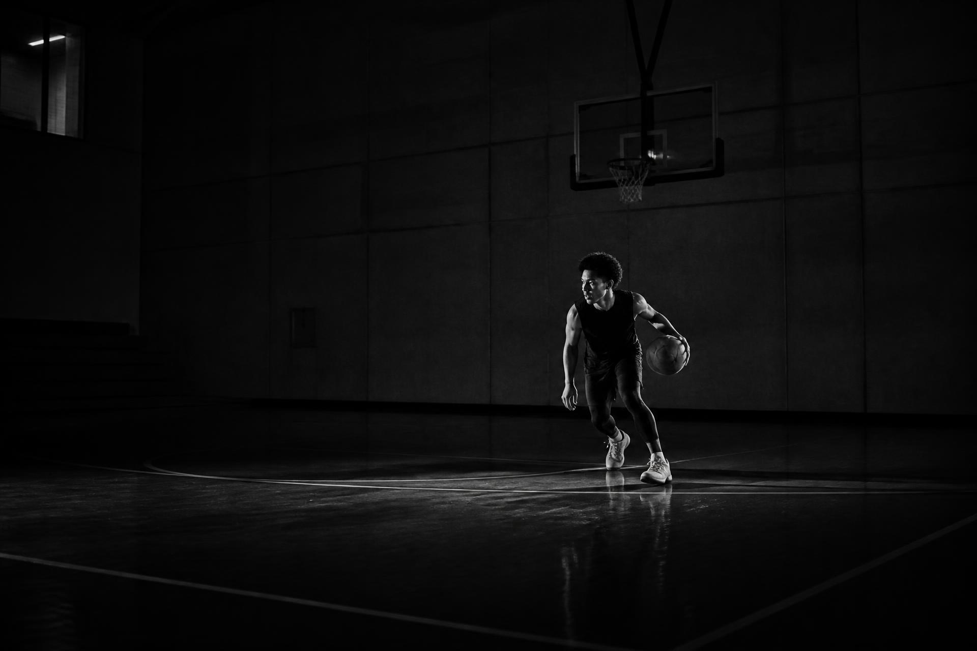 Basketball athlete training alone in a dark gym